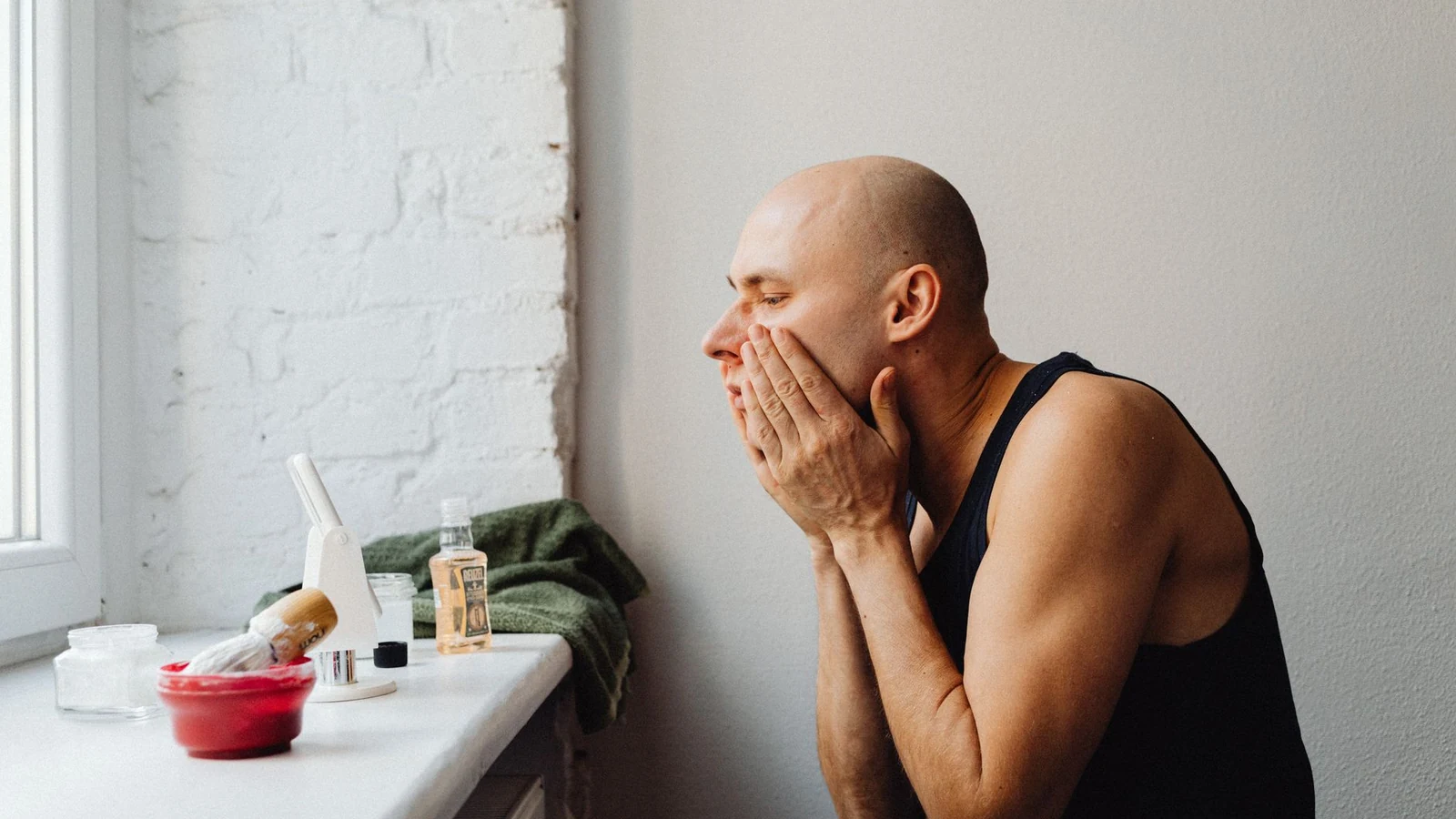 A man applies skincare in a natural-lit bathroom, reflecting self-care and grooming habits. — selected for United Kingdom readers