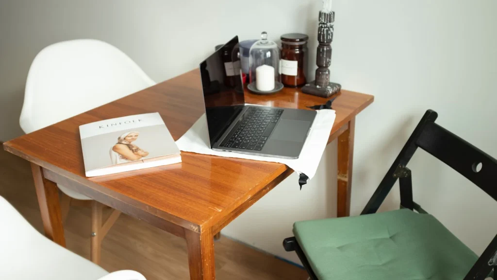 Stylish home office desk with laptop, magazine, and candles, creating a cozy work environment. — selected for United States readers