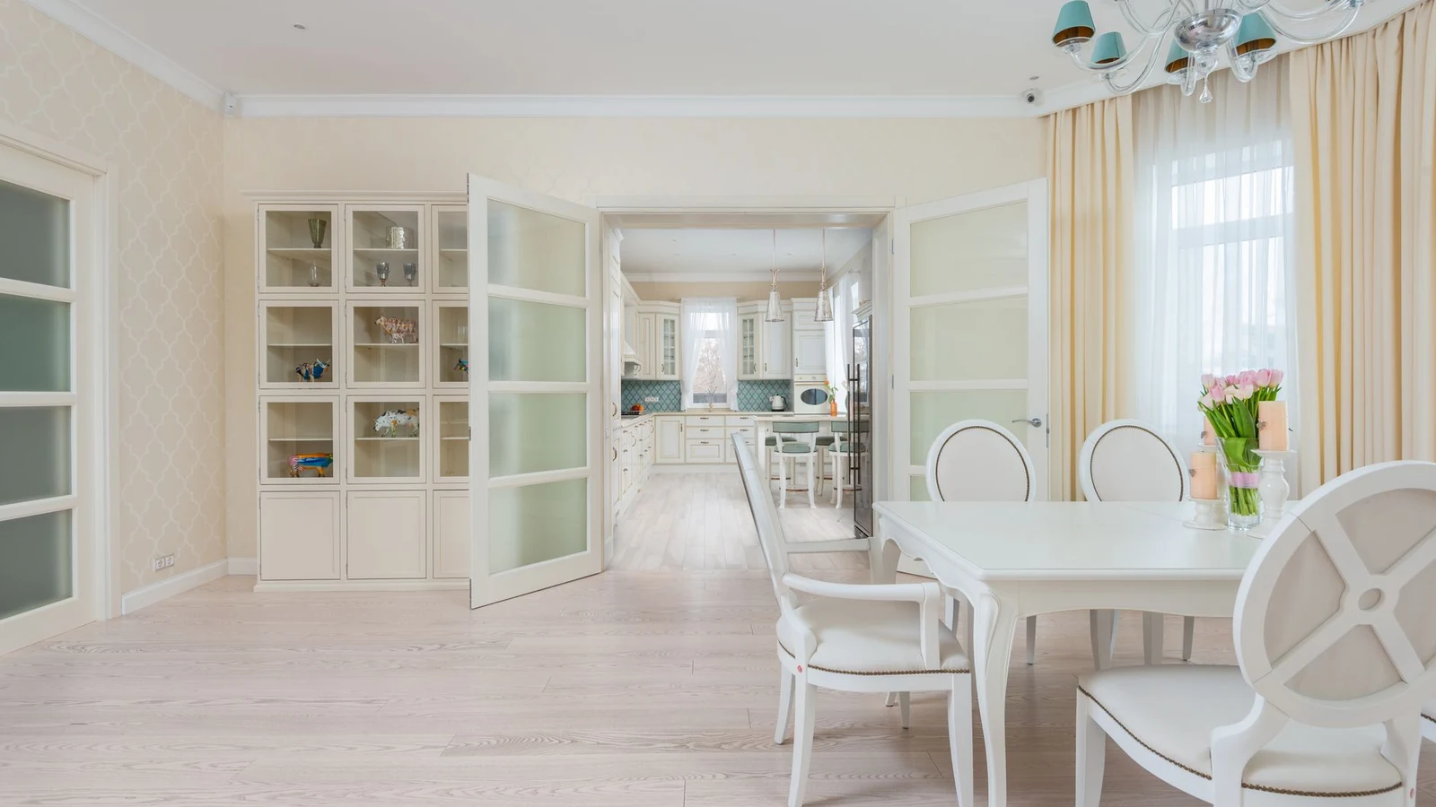 Interior of spacious light dining room with white table and cozy chairs near large window with curtains — selected for United Kingdom readers