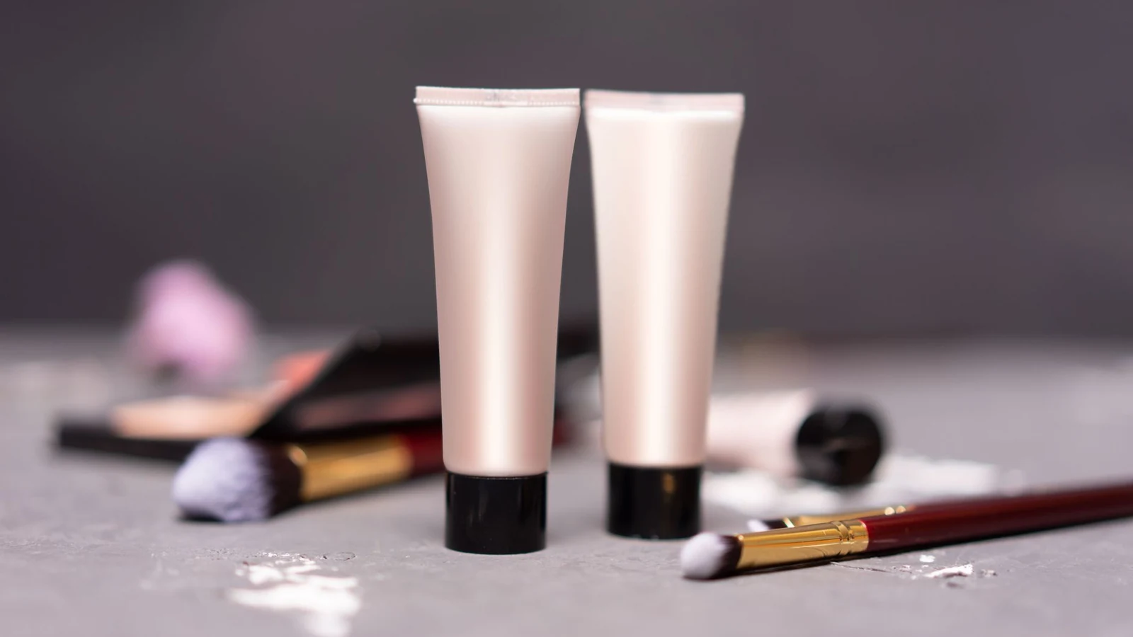 Close-up of skincare tubes with makeup brushes on a table, symbolizing beauty and self-care. — selected for United Kingdom readers