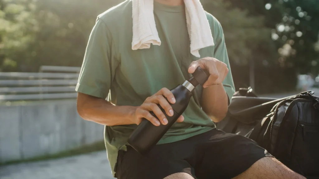 Close-up of a man sitting outdoors with a reusable water bottle and towel. — selected for United Kingdom readers