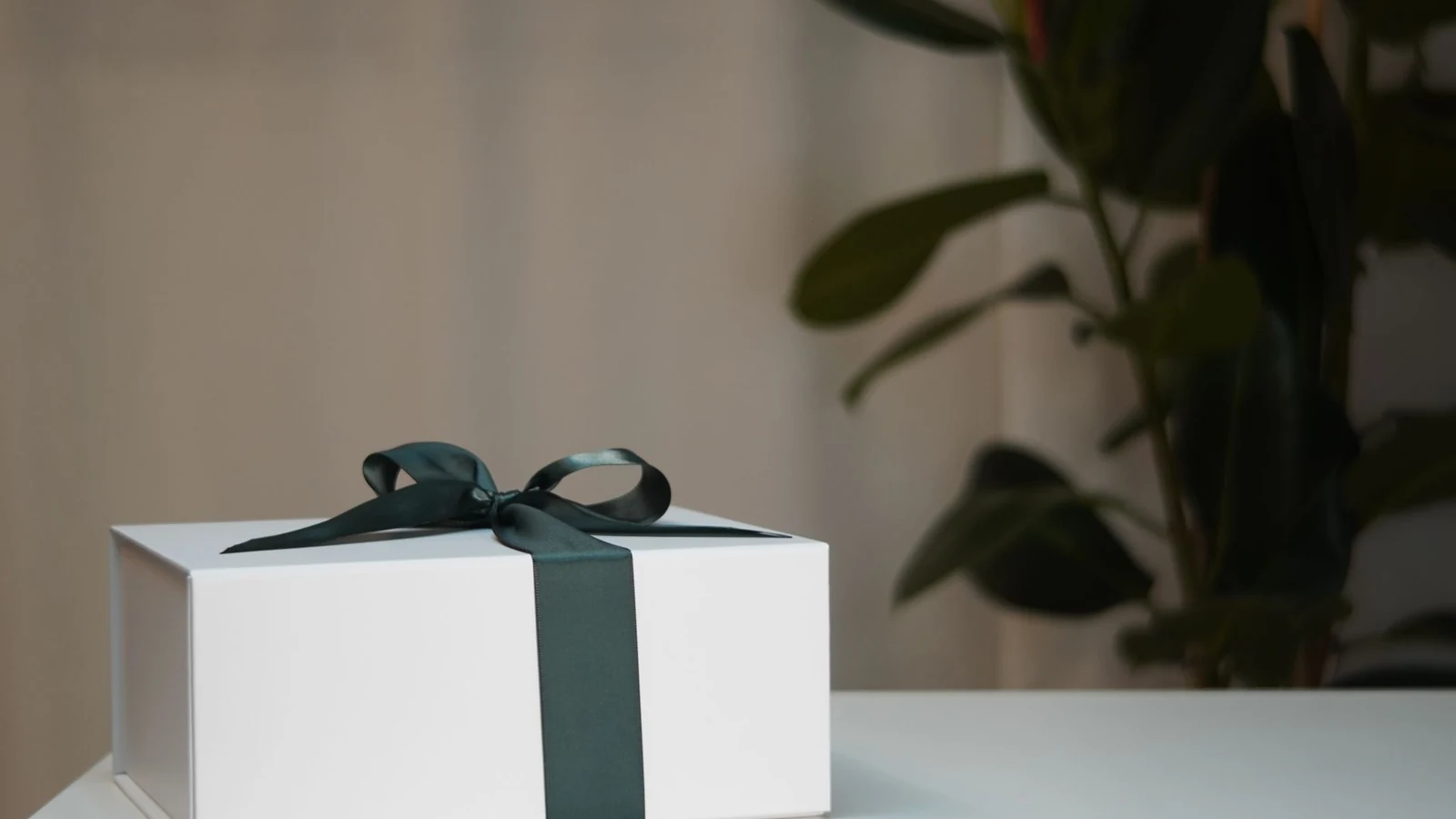 White gift box with dark ribbon on table, minimalistic setup, perfect for celebrations and surprises. — selected for United Kingdom readers