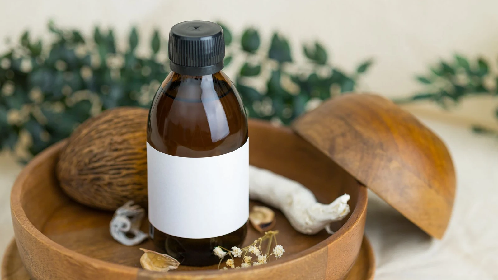 A brown glass bottle with a blank label placed on a wooden plate surrounded by botanical elements, ideal for cosmetic and natural product themes. — selected for United Kingdom readers