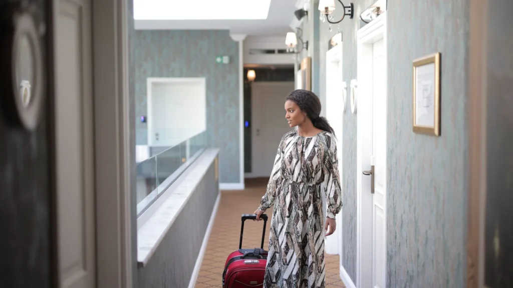A woman walks with luggage through a stylish hotel corridor, embodying travel elegance. — selected for United States readers