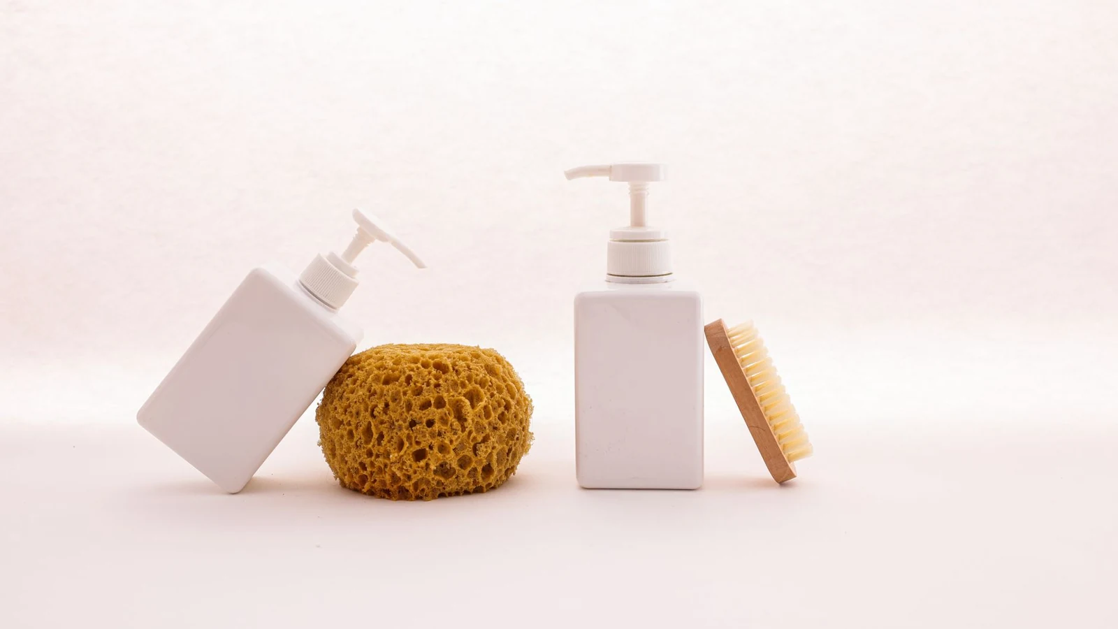 Clean white pump bottles paired with a sponge and brush for a simple bathroom elegance. — selected for United Kingdom readers
