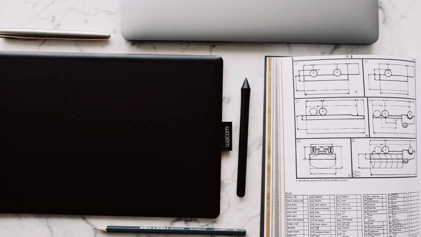 From above of opened sketchbook with drawn scheme and tablet with black screen located near sharp pencil and marker — selected for United States readers