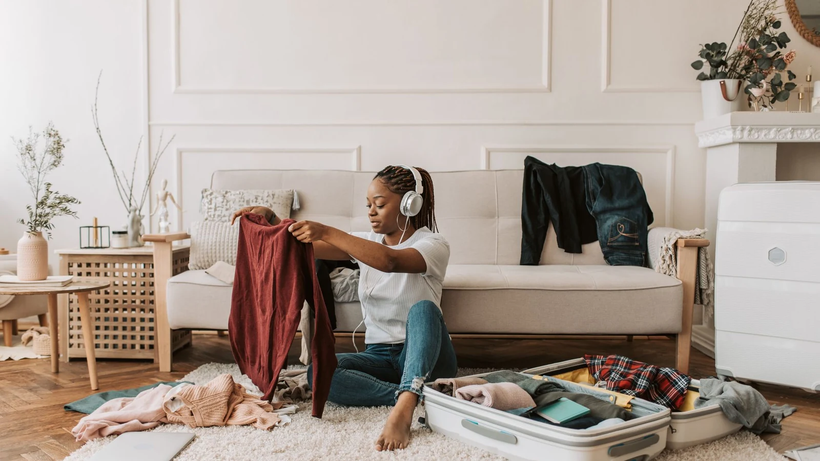 Woman preparing for travel at home, packing luggage, and listening to music. — selected for United States readers
