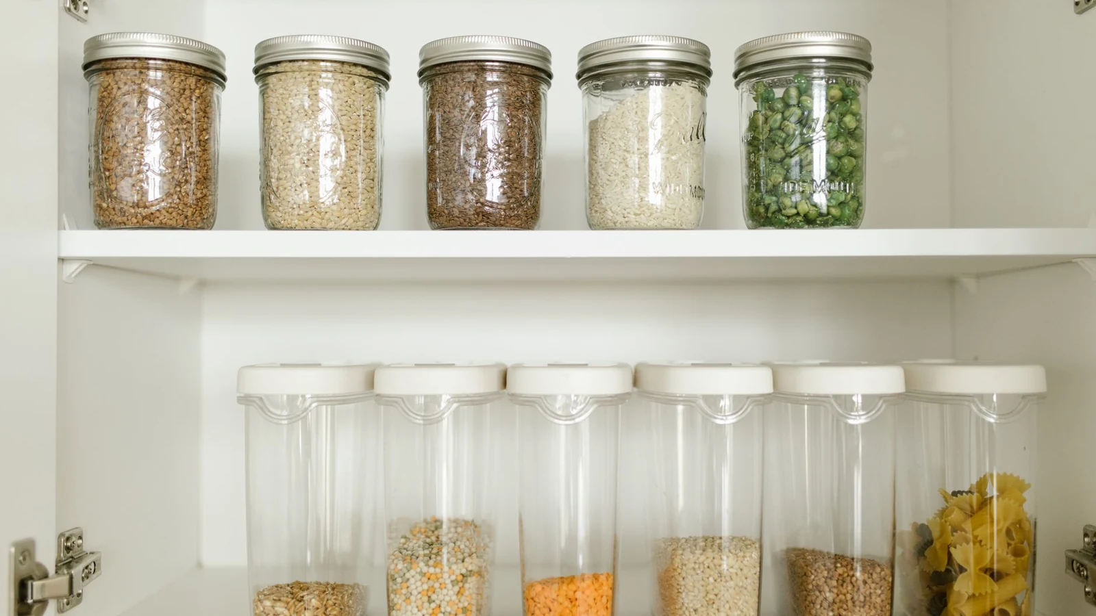 Neatly arranged pantry showcasing grains in glass jars and dry goods in plastic containers. — selected for United States readers