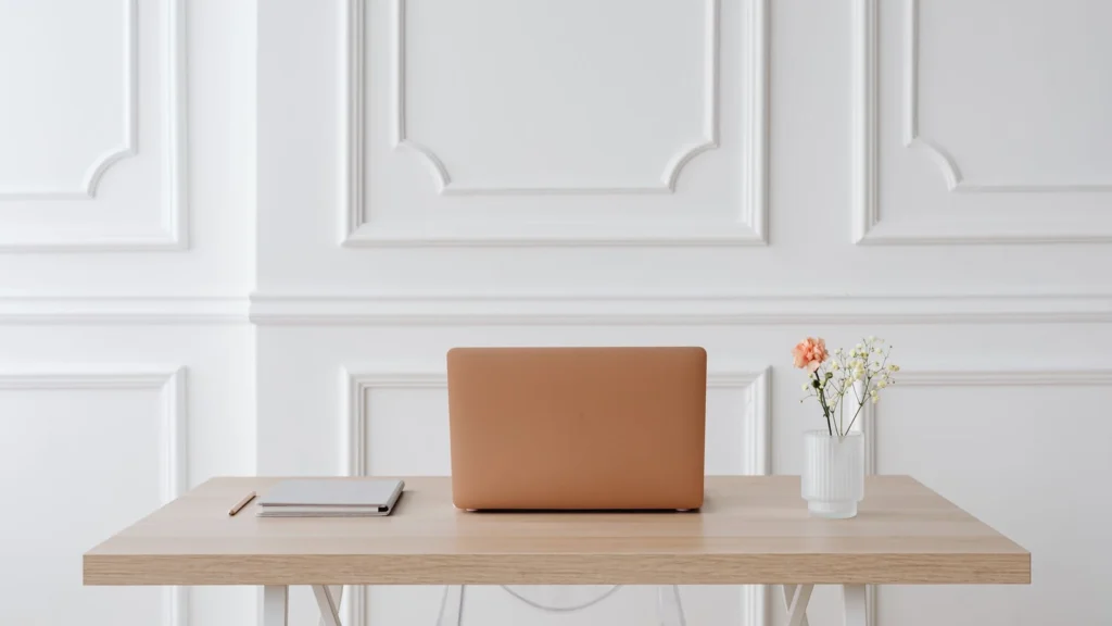 A serene workspace featuring a simple desk with a laptop, notebook, and a vase of flowers. — selected for United States readers