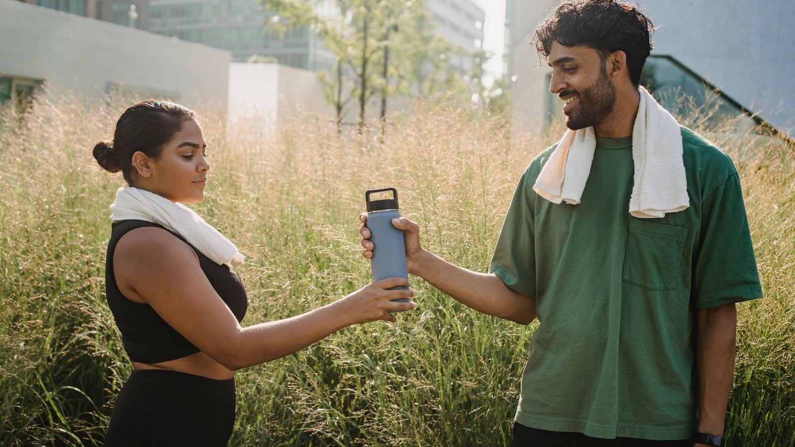 A man and woman sharing a water bottle during an outdoor workout session. — selected for United Kingdom readers