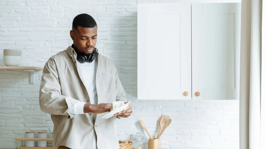 African American man with headphones cleaning a plate in a stylish kitchen setting. — selected for United States readers