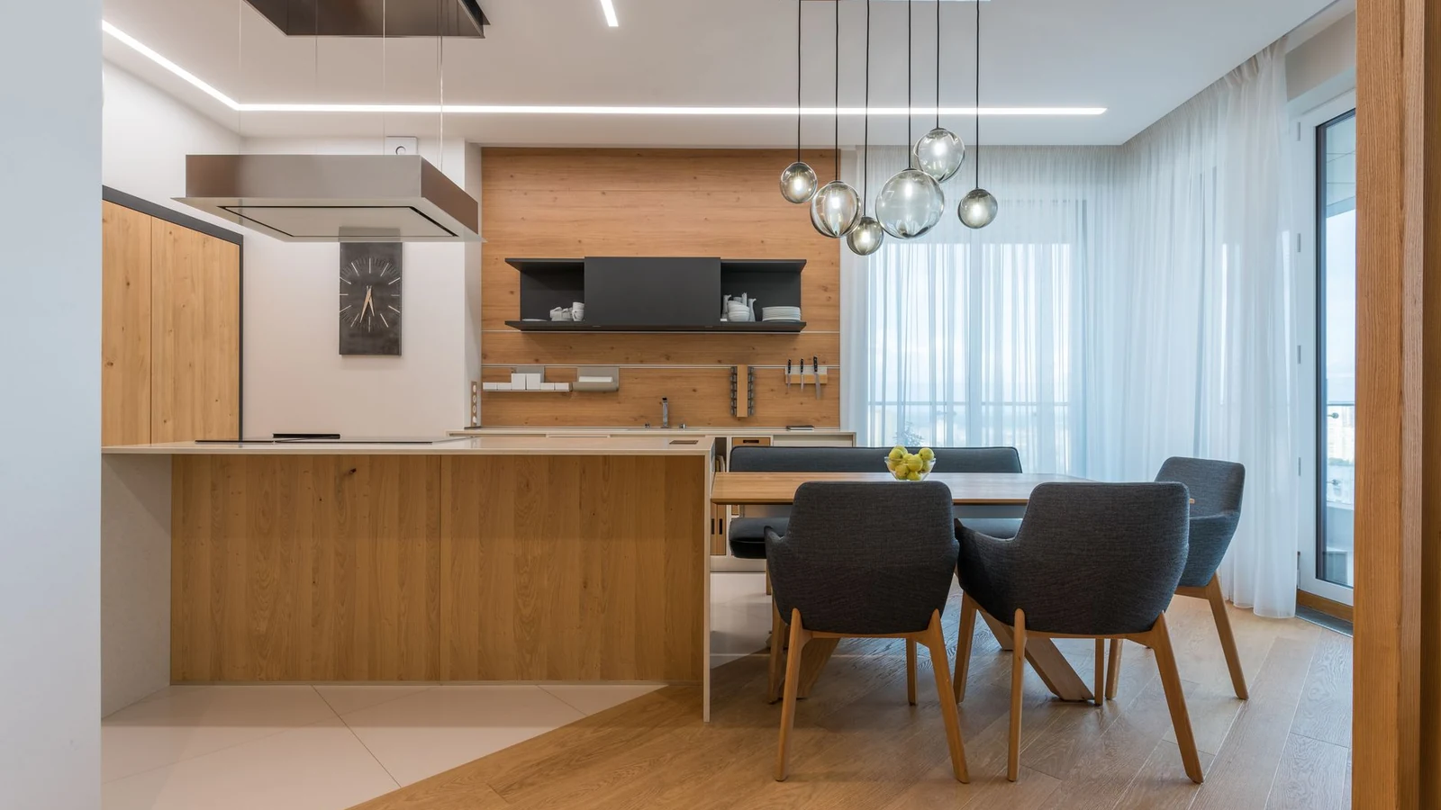 Interior of contemporary kitchen with wooden furniture and floor and dining table with soft chairs in cozy apartment — selected for United Kingdom readers