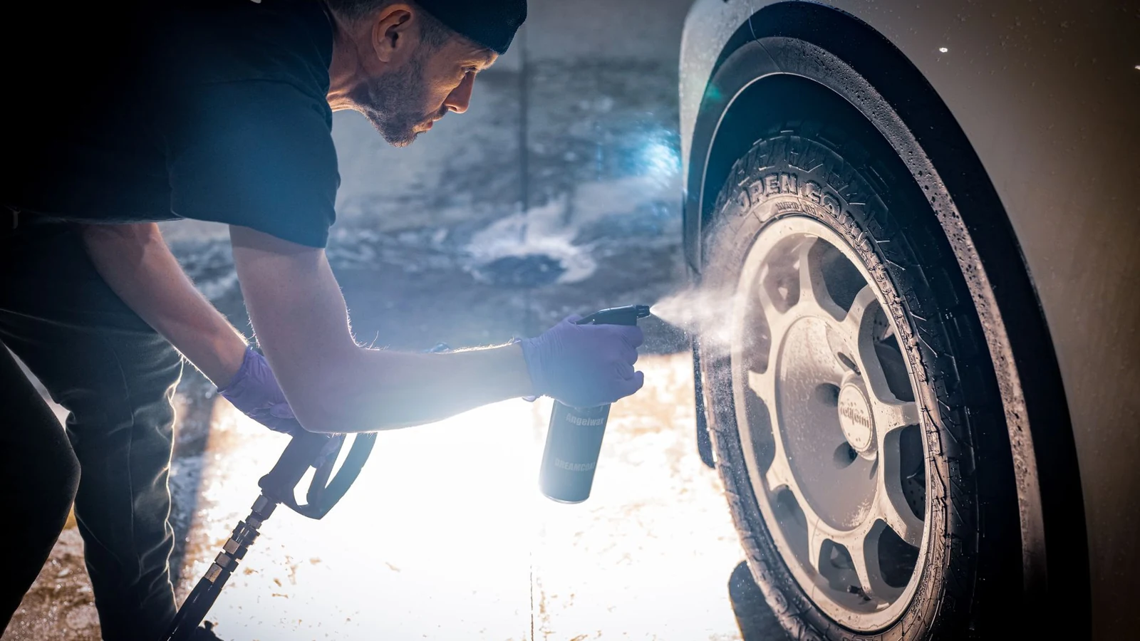 A man meticulously cleaning a car tire with a spray bottle in a vehicle detailing shop. — selected for United Kingdom readers