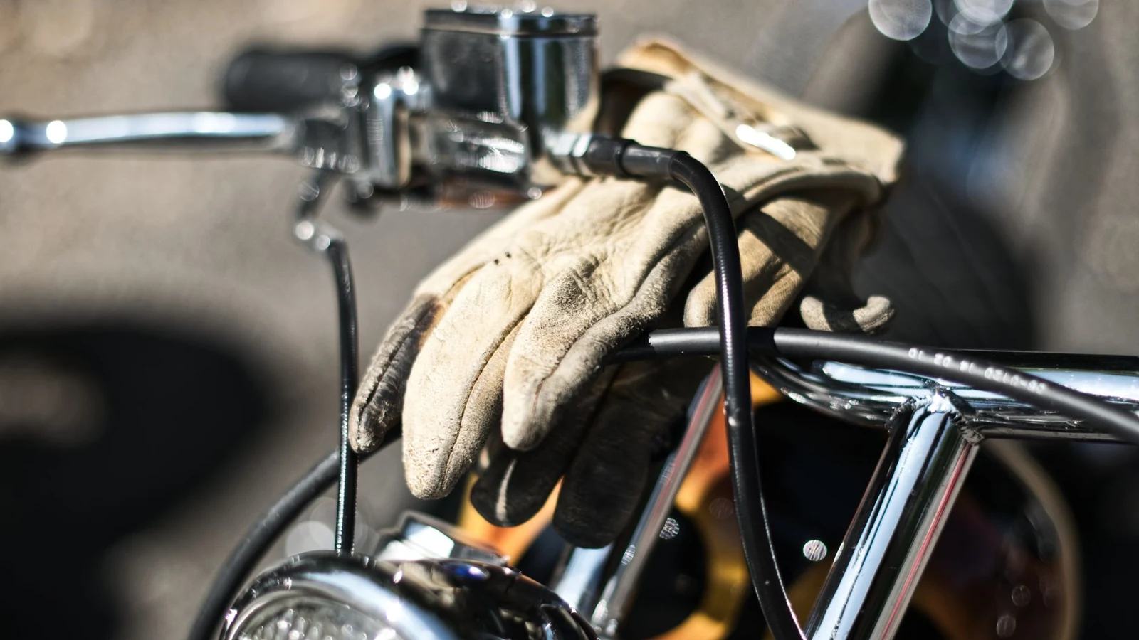 Vintage motorcycle handlebars with leather gloves draped over, highlighting classic chrome details. — selected for United States readers