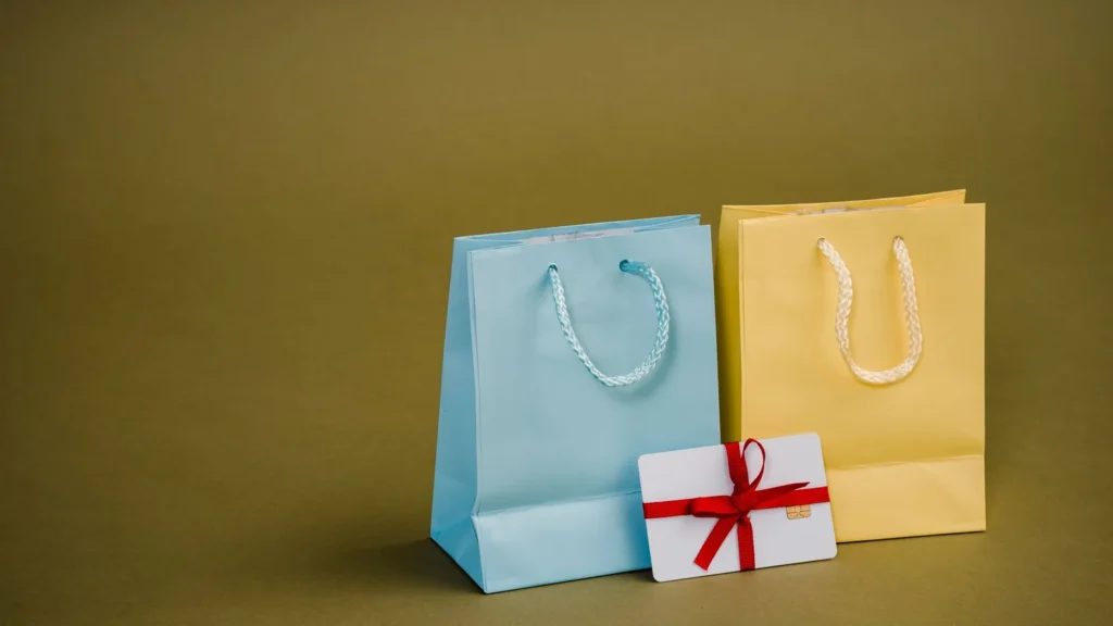 Collection of bright present paper bags with natural handles near gift card with ribbon — selected for United Kingdom readers