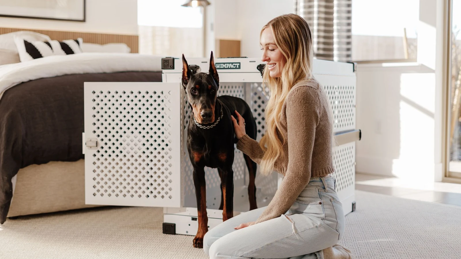 A young woman sitting by a Doberman in a modern bedroom with natural light. — selected for United States readers