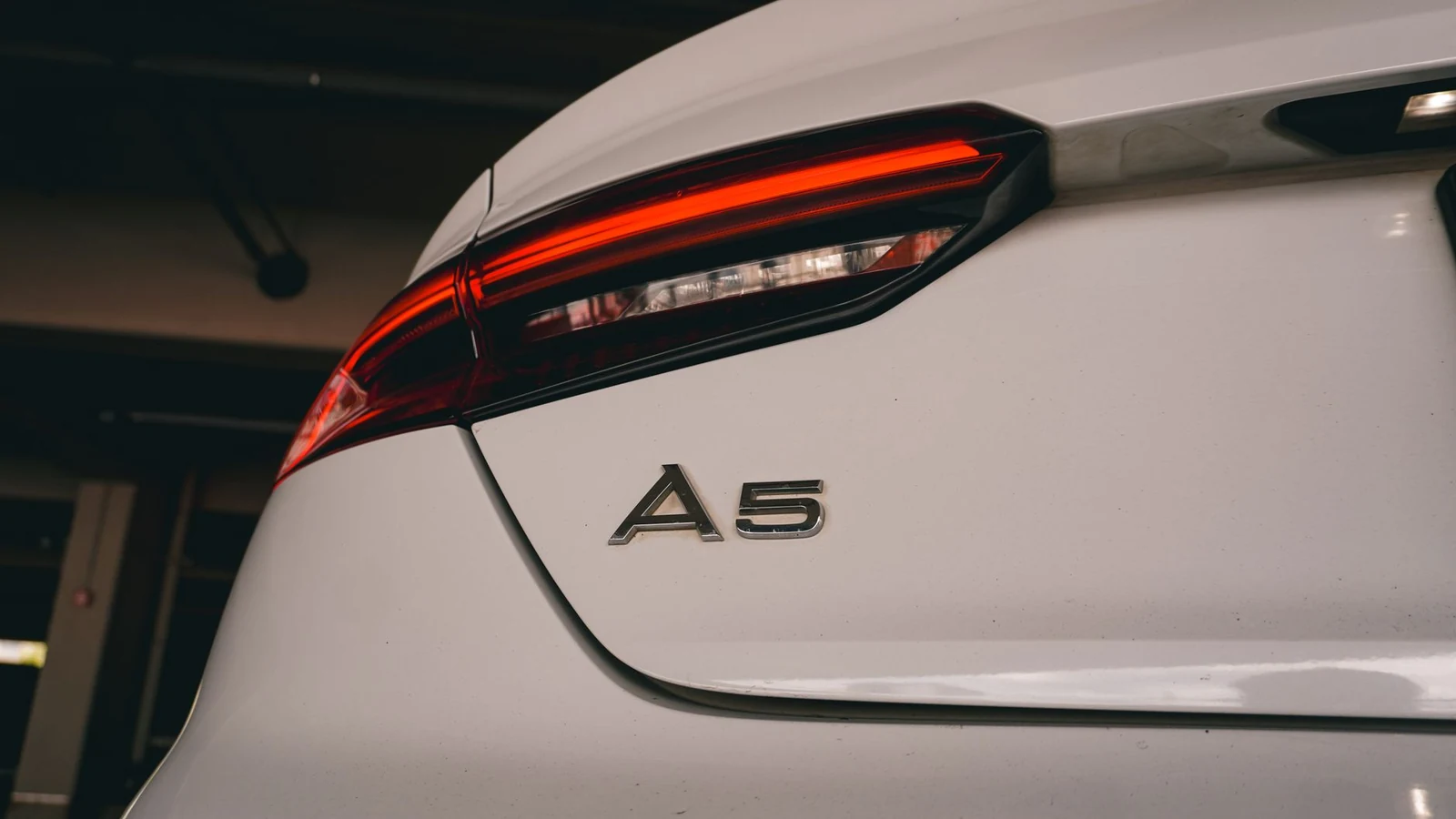 Detailed view of a car's rear tail light and badge in a parking garage. — selected for United Kingdom readers